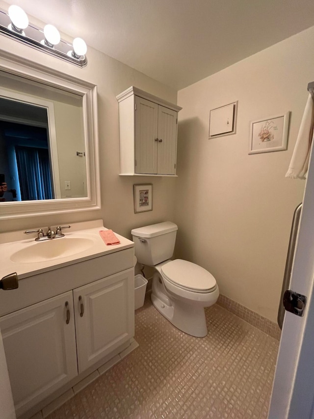 bathroom with toilet, vanity, and tile patterned floors