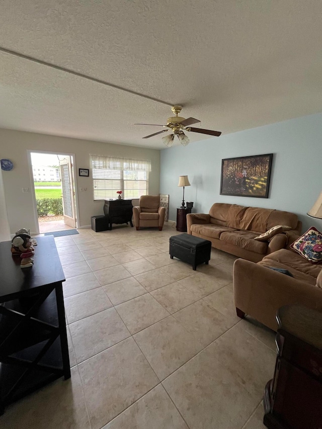 living room featuring a textured ceiling, ceiling fan, and light tile patterned flooring