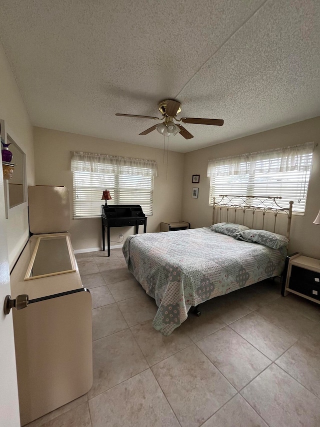 tiled bedroom with multiple windows, a textured ceiling, and ceiling fan