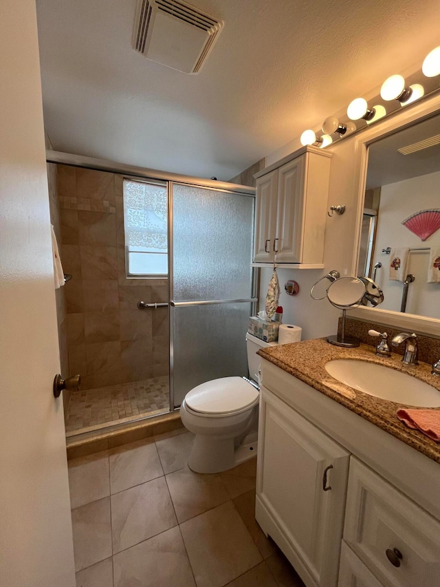 bathroom with vanity, a shower with door, tile patterned floors, and toilet