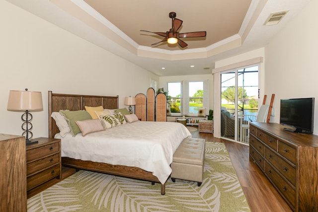 bedroom featuring a tray ceiling, access to exterior, ceiling fan, and light wood-type flooring