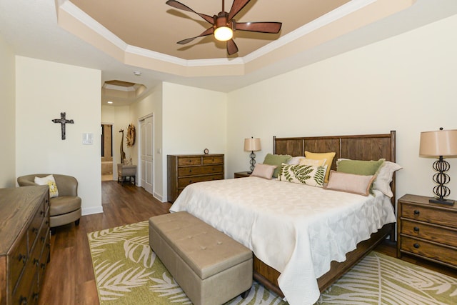 bedroom featuring ceiling fan, a raised ceiling, crown molding, wood-type flooring, and a closet