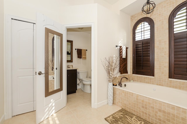 bathroom featuring tile patterned floors, tiled bath, vanity, and toilet