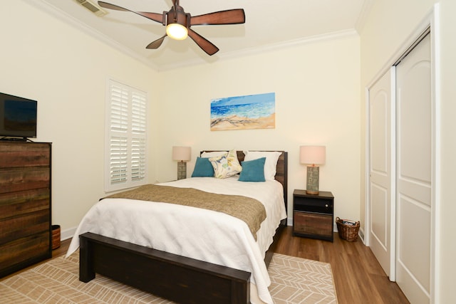 bedroom with hardwood / wood-style flooring, ceiling fan, ornamental molding, and a closet