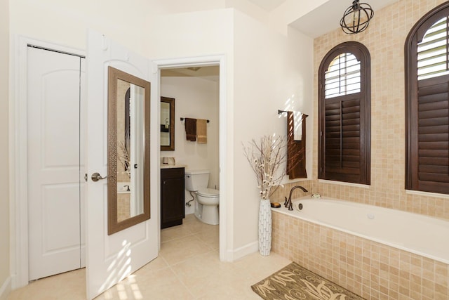 bathroom featuring vanity, a relaxing tiled tub, toilet, and tile patterned floors