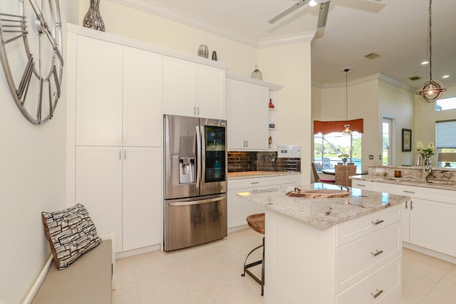 kitchen featuring white cabinets, stainless steel refrigerator with ice dispenser, a center island, and sink