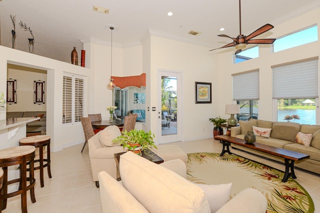 tiled living room with ceiling fan, a high ceiling, and ornamental molding