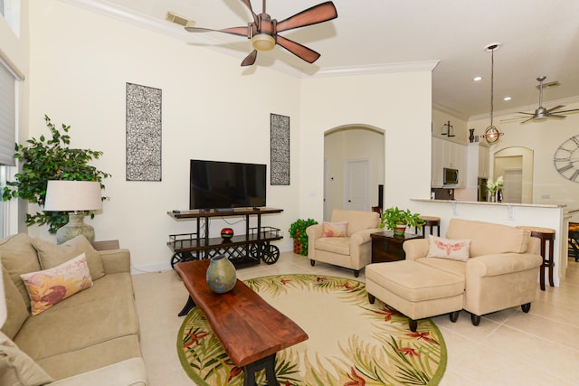 living room featuring ceiling fan, a towering ceiling, light tile patterned flooring, and ornamental molding