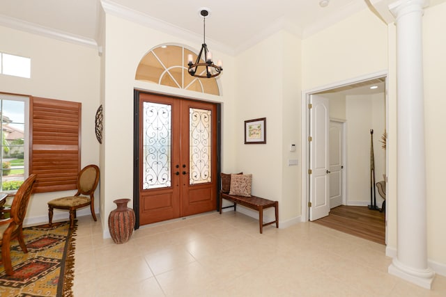 foyer entrance with french doors, an inviting chandelier, ornate columns, and crown molding