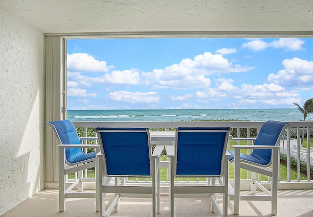 balcony featuring a beach view and a water view