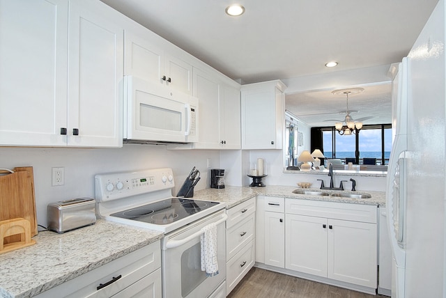 kitchen with white cabinetry, white appliances, sink, a chandelier, and light hardwood / wood-style flooring