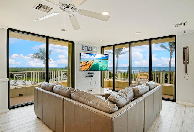 living room with a wall of windows, light hardwood / wood-style flooring, and ceiling fan