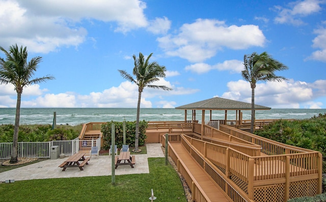 exterior space featuring a patio area, a water view, and a view of the beach