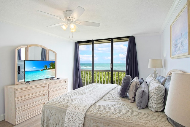 bedroom with crown molding, light wood-type flooring, a textured ceiling, access to exterior, and ceiling fan