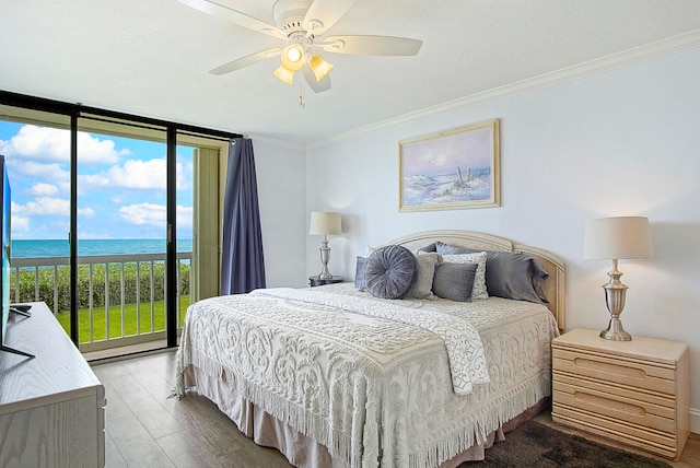 bedroom with hardwood / wood-style flooring, a water view, ceiling fan, expansive windows, and crown molding