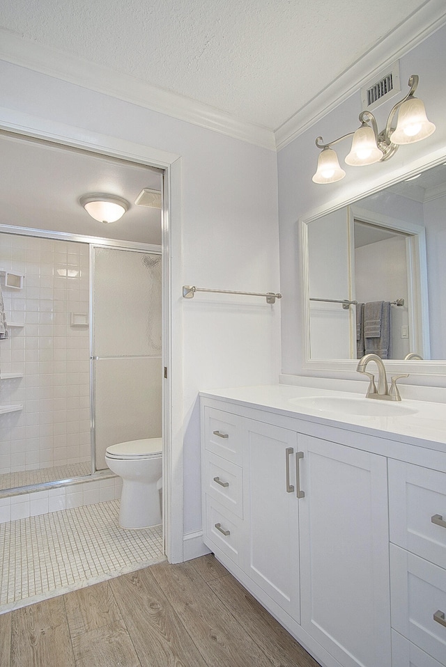 bathroom with a shower with door, ornamental molding, a textured ceiling, hardwood / wood-style floors, and toilet