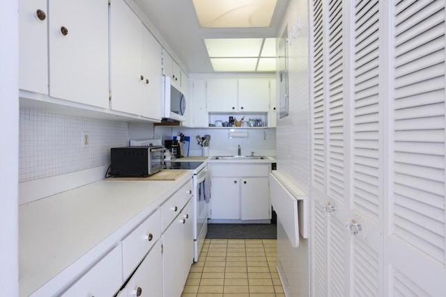 kitchen featuring white cabinets, light tile patterned flooring, sink, and white appliances