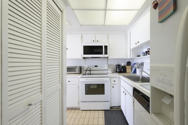 kitchen featuring light tile patterned flooring, sink, tasteful backsplash, white appliances, and white cabinets