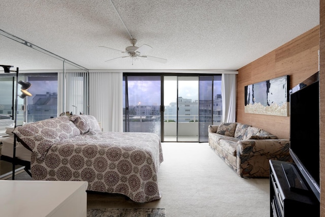 bedroom with a wall of windows, access to exterior, ceiling fan, and a textured ceiling