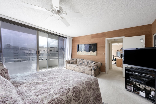 bedroom with light colored carpet, wood walls, a textured ceiling, floor to ceiling windows, and ceiling fan