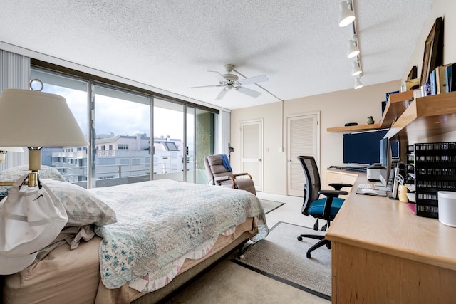 bedroom with track lighting, ceiling fan, a textured ceiling, access to exterior, and expansive windows