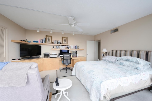 bedroom featuring rail lighting, ceiling fan, and built in desk