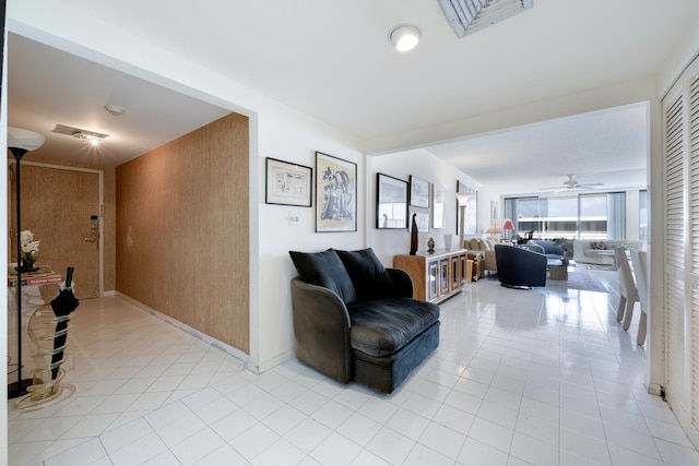 living room with wooden walls, ceiling fan, and light tile patterned floors