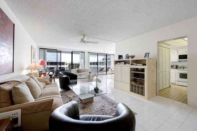 tiled living room featuring a textured ceiling, ceiling fan, and floor to ceiling windows