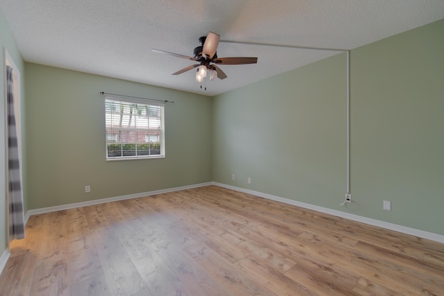 empty room featuring a ceiling fan, baseboards, a textured ceiling, and light wood finished floors