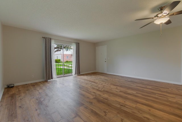 empty room with ceiling fan, baseboards, a textured ceiling, and wood finished floors