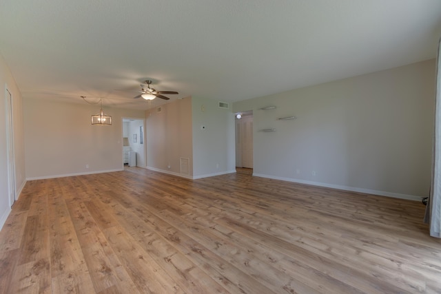 unfurnished living room with light wood finished floors, baseboards, visible vents, and ceiling fan with notable chandelier