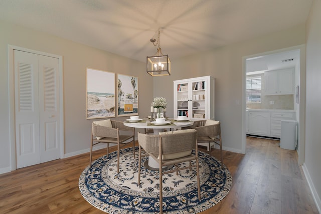 dining space with visible vents, light wood-style floors, baseboards, and a chandelier