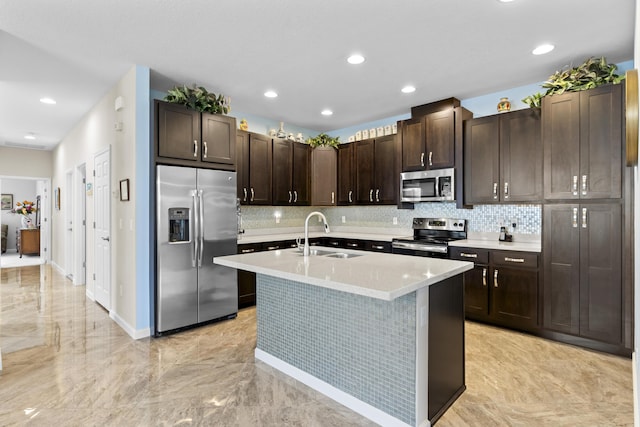 kitchen with a center island with sink, stainless steel appliances, backsplash, dark brown cabinets, and sink