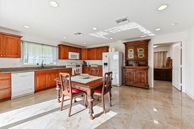 kitchen featuring white appliances, sink, and dark stone counters