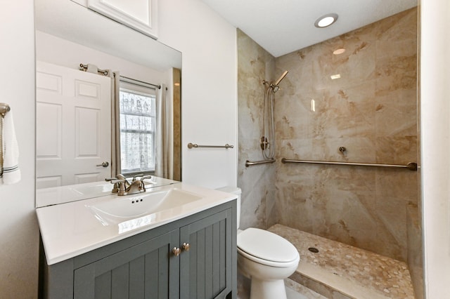 bathroom featuring tiled shower, vanity, and toilet