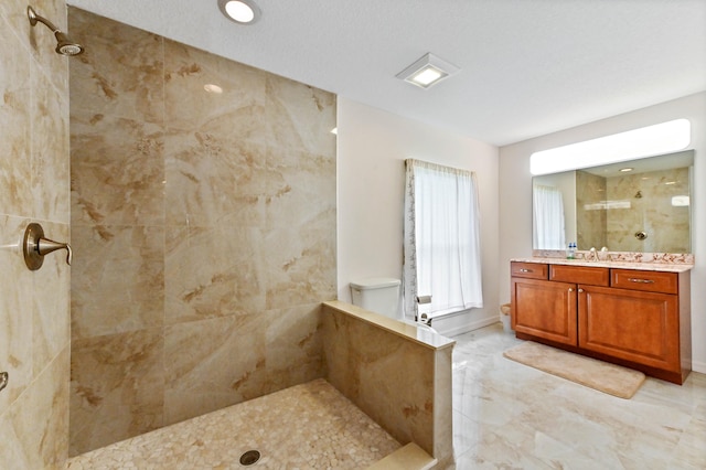 bathroom with vanity, a textured ceiling, and tiled shower