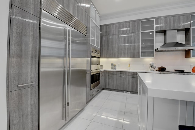 kitchen featuring stainless steel appliances, crown molding, gray cabinetry, and wall chimney exhaust hood