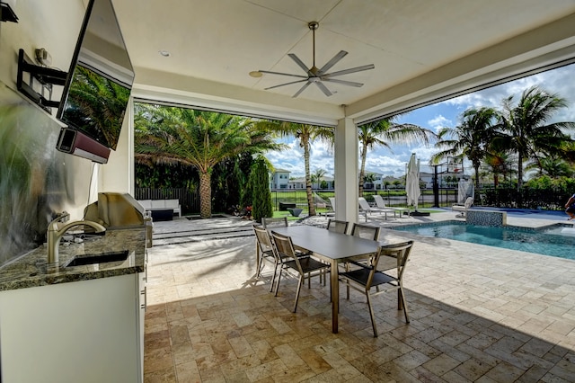 view of patio / terrace with an outdoor kitchen, an outdoor wet bar, pool water feature, ceiling fan, and a swimming pool with hot tub