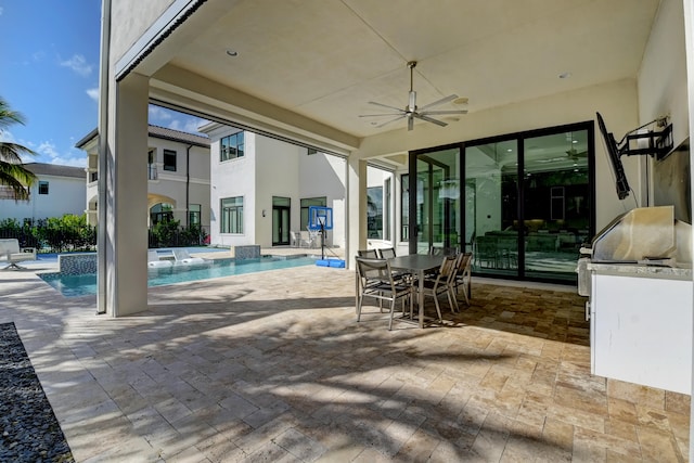 exterior space with an outdoor kitchen, a jacuzzi, pool water feature, ceiling fan, and a patio