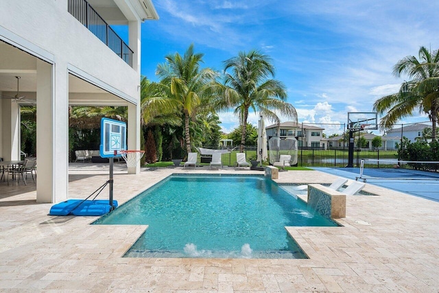 view of swimming pool with pool water feature, a water view, and a patio