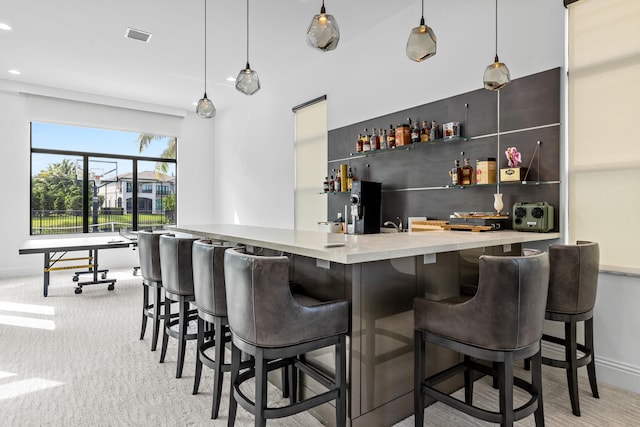 bar with pendant lighting and light colored carpet