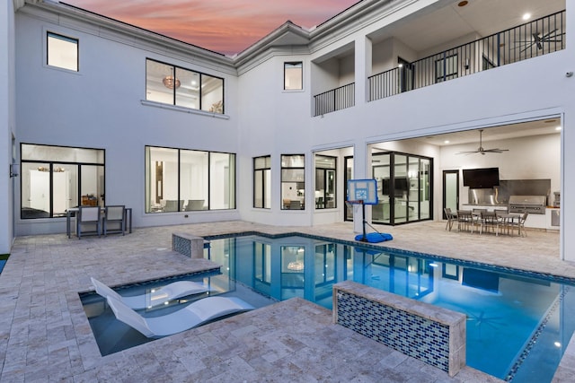 pool at dusk with grilling area, ceiling fan, and a patio area