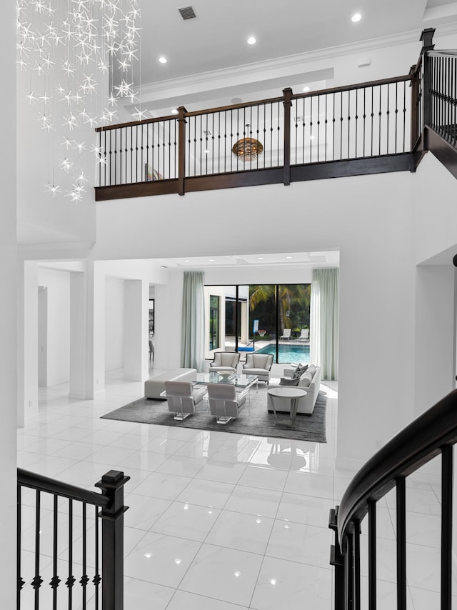 interior space with tile patterned flooring, ornamental molding, a towering ceiling, and french doors