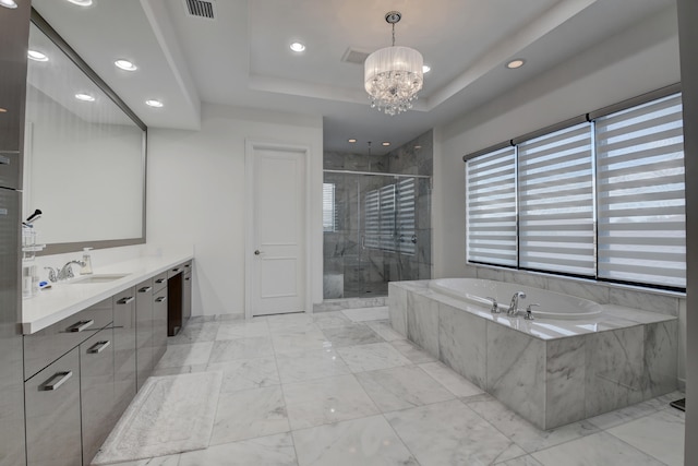 bathroom featuring a tray ceiling, a chandelier, vanity, and independent shower and bath