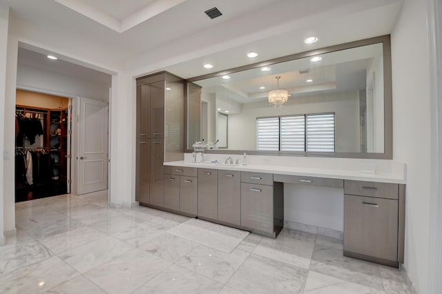 bathroom with a chandelier, vanity, and a tray ceiling