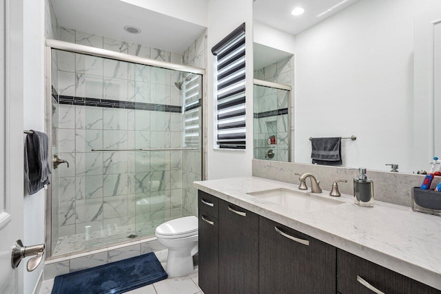 bathroom with tile patterned floors, vanity, a shower with shower door, and toilet