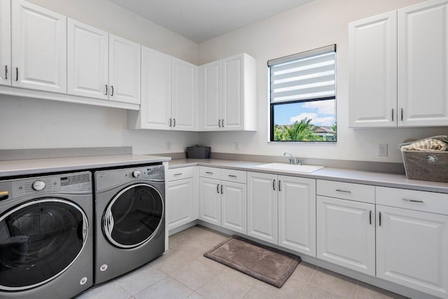 clothes washing area with washing machine and clothes dryer, light tile patterned flooring, cabinets, and sink