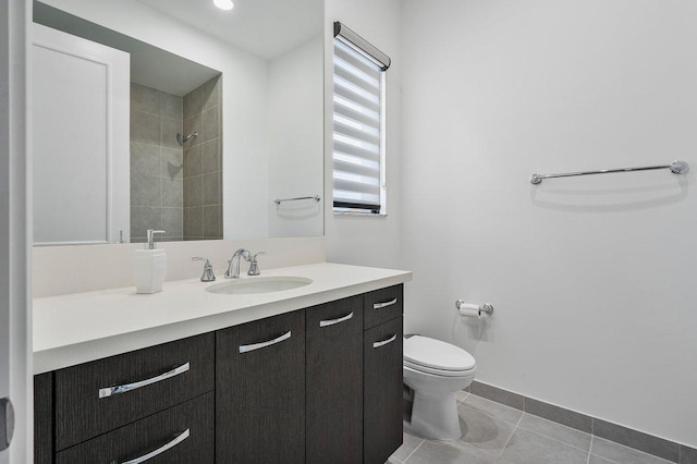 bathroom featuring toilet, vanity, tiled shower, and tile patterned floors