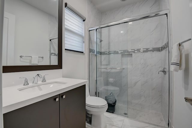 bathroom featuring vanity, a shower with shower door, and toilet