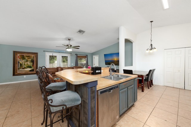 kitchen featuring lofted ceiling, a center island with sink, sink, hanging light fixtures, and stainless steel dishwasher